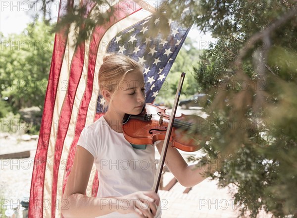 Caucasian girl playing violin near American flag