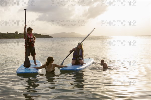 Caucasian family swimming and using paddleboards