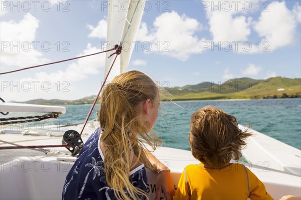 Wind blowing hair of Caucasian brother and sister in sailboat
