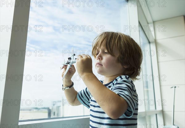 Caucasian boy playing with toy airplane near window