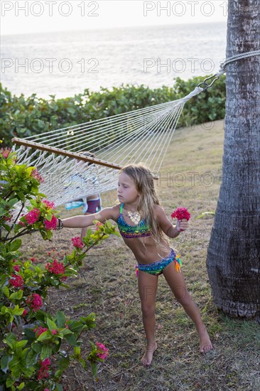 Caucasian girl wearing a bikini picking flowers