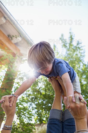 Caucasian boy balancing on feet of mother