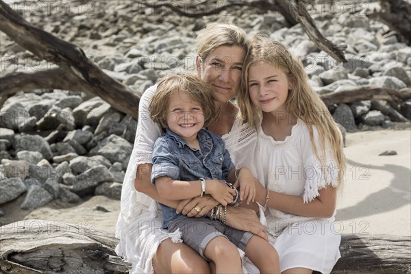 Caucasian family sitting on driftwood at beach