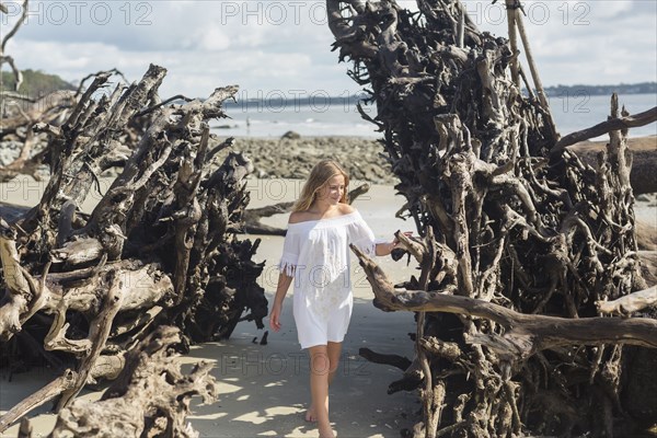 Caucasian girl admiring driftwood on beach