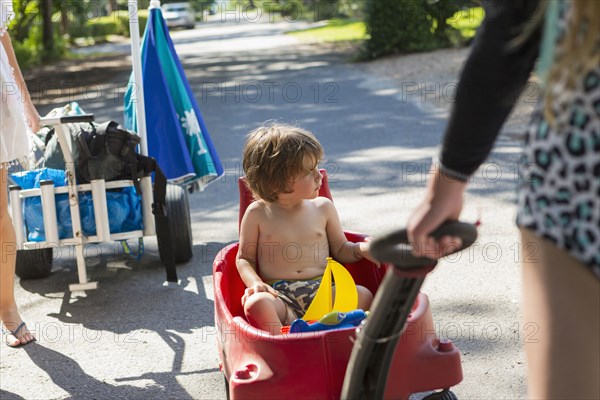 Caucasian boy riding in red wagon