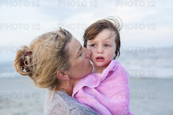 Caucasian mother holding son at beach