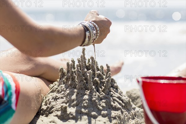 Caucasian woman playing with sand castle at beach