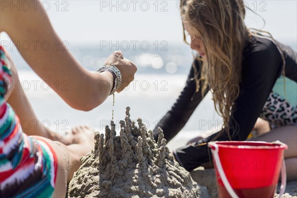 Caucasian mother and daughter playing with sand castle at the beach