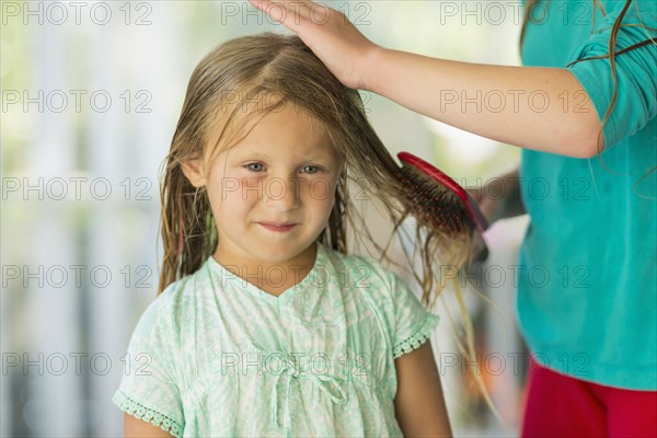 Caucasian girl brushing wet hair of sister