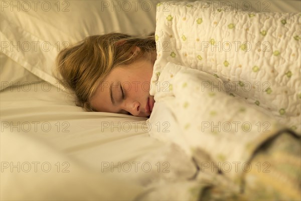 Caucasian girls sleeping in bed under blanket