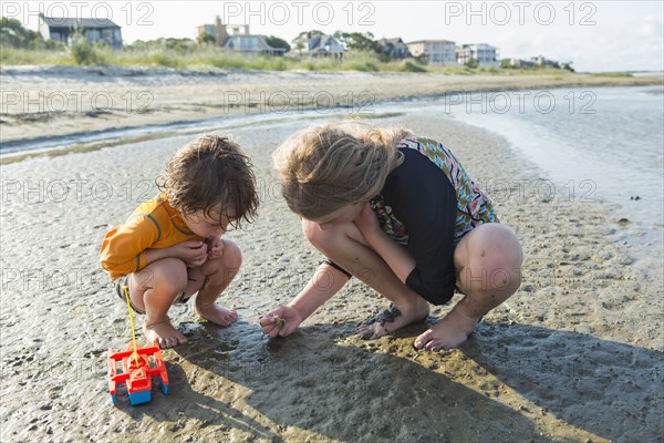 Caucasian brother and sister searching on beach