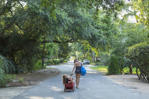 Caucasian mother pulling son and daughter in wagon