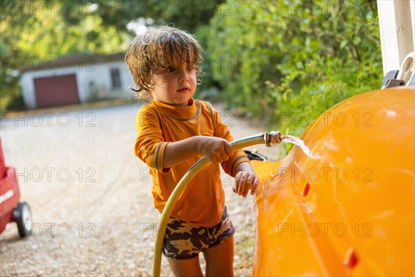 Caucasian boy washing kayak with hose