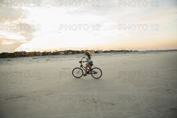 Caucasian girl riding bicycle on beach