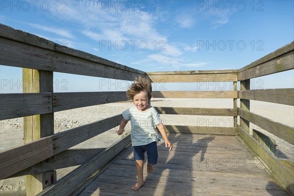 Caucasian boy walking on windy boardwalk