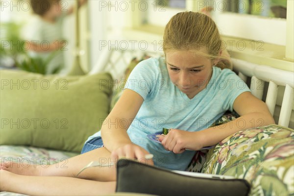 Caucasian girl sitting on sofa watching digital tablet