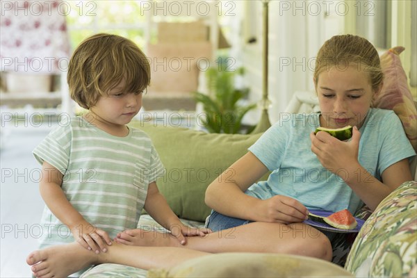 Caucasian brother and sister watching digital tablet on sofa