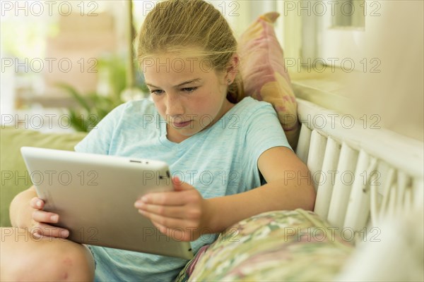 Caucasian girl sitting on sofa watching digital tablet