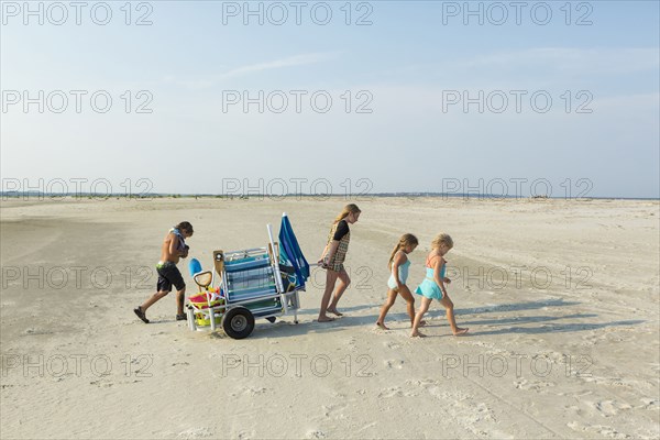 Caucasian boy and girls pulling cart on beach