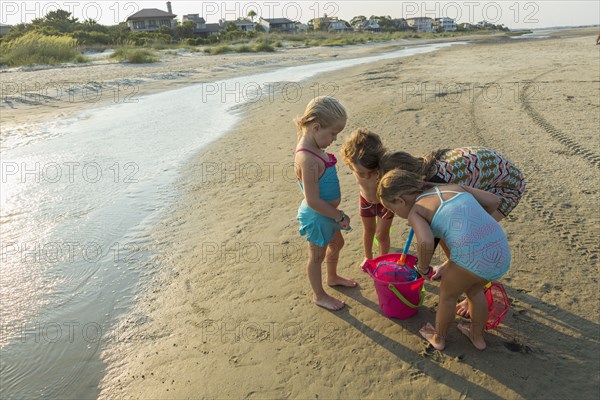 Caucasian boy and girls playing with pail on beach