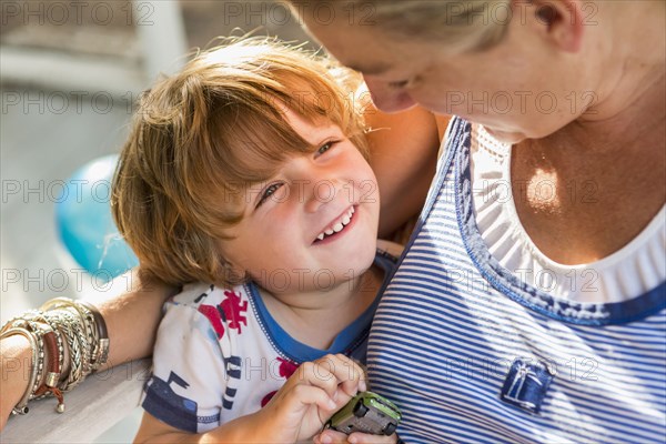 Caucasian mother hugging son holding toy car