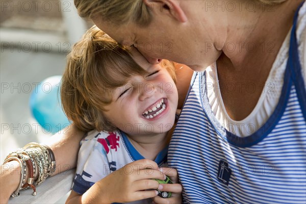 Caucasian mother hugging laughing son holding toy car