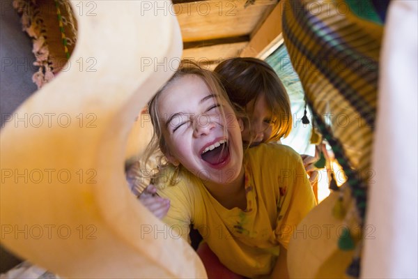 Caucasian brother and sister laughing under table