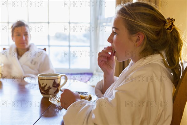 Caucasian girl eating breakfast in bathrobe