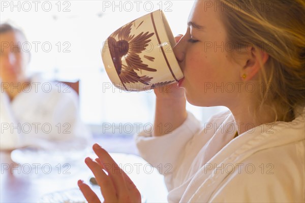 Caucasian girl drinking coffee in bathrobe