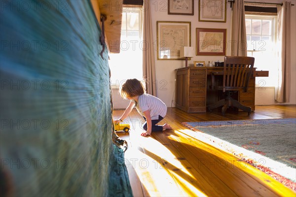 Caucasian boy on the floor playing with toy truck