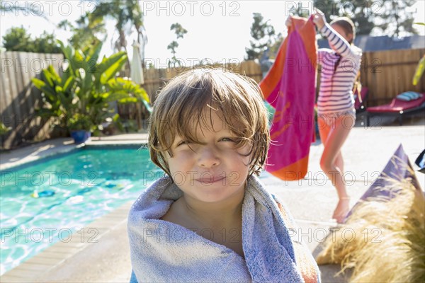 Caucasian boy wrapped in towel near swimming pool