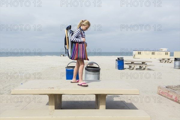 Caucasian girl standing on picnic table at beach