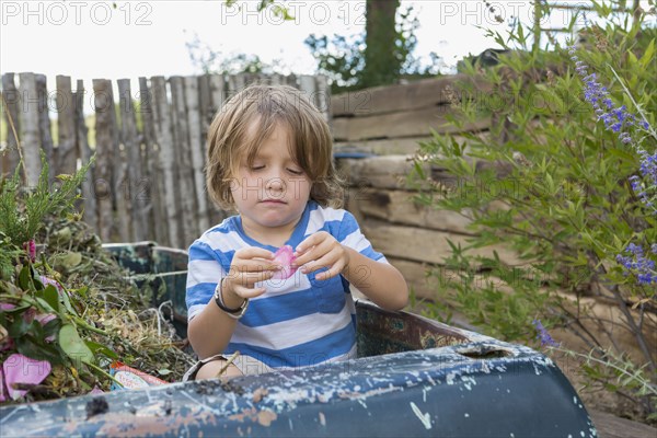 Caucasian boy sitting in truck playing with flower petal