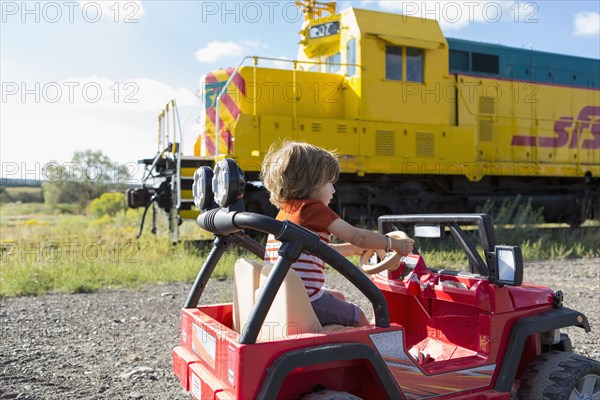 Caucasian boy driving toy car near train