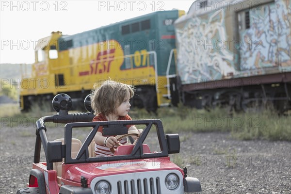 Caucasian boy driving toy car near train