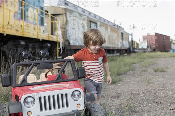 Caucasian boy holding toy car near train