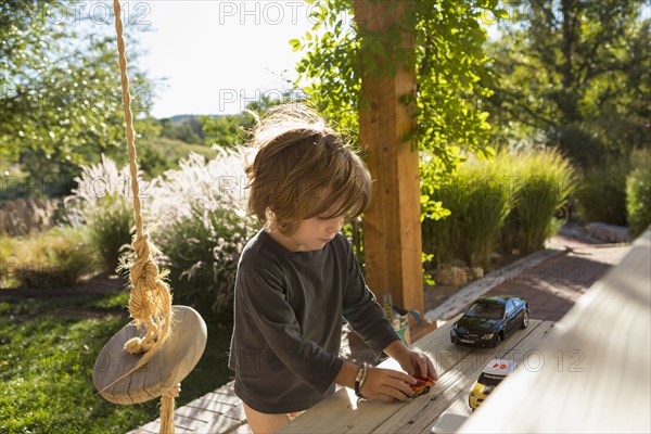 Caucasian boy playing with toy cars on patio