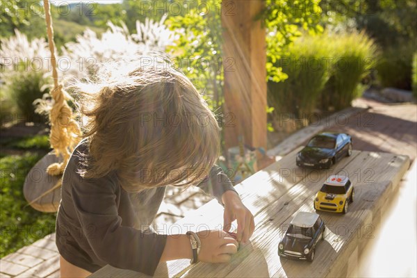 Sunshine on a Caucasian boy playing with toy cars