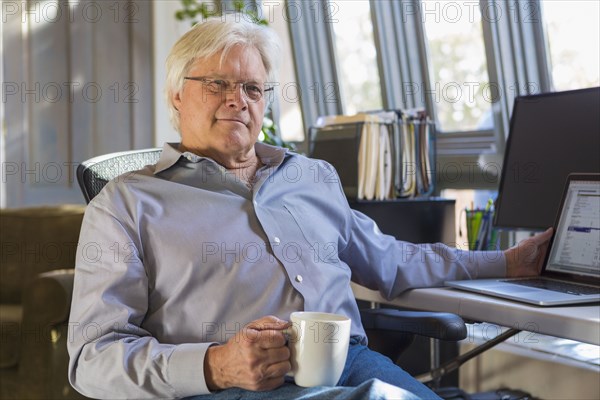 Caucasian man drinking coffee and using laptop