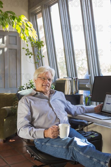 Caucasian man drinking coffee and using laptop