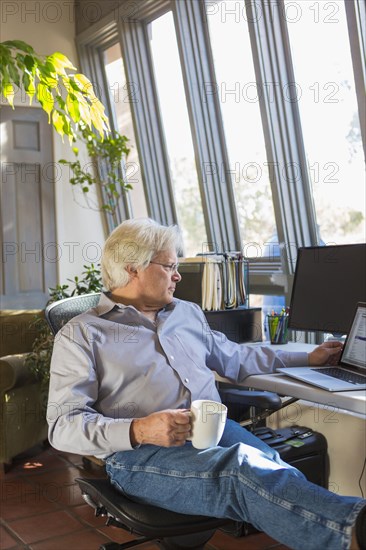 Caucasian man drinking coffee and using laptop