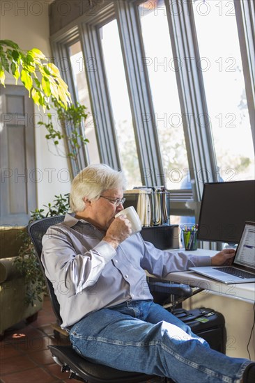 Caucasian man drinking coffee and using laptop