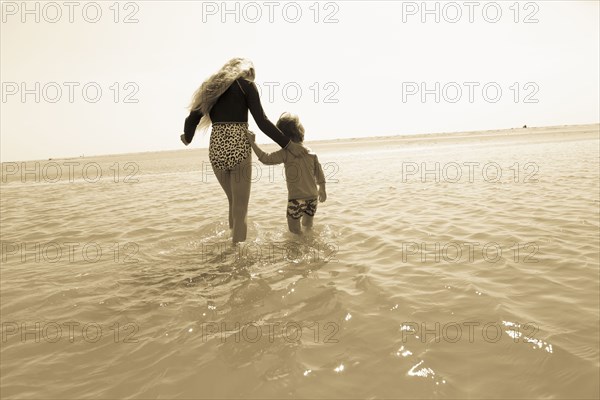 Caucasian brother and sister wading in ocean