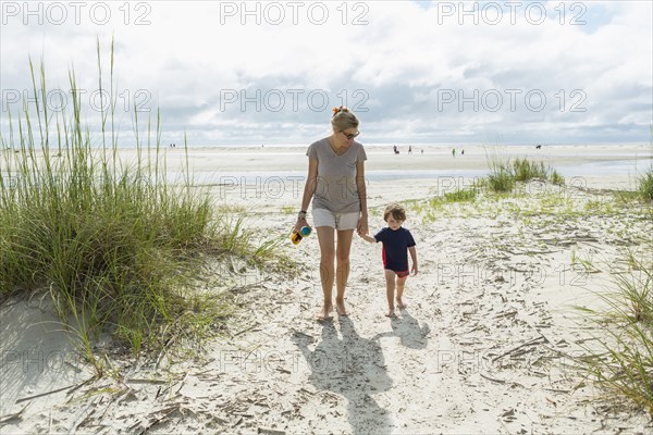 Caucasian mother and son walking on beach