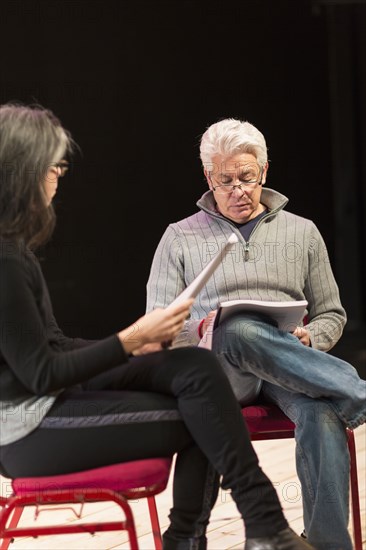 Hispanic man and woman reading scripts on theater stage