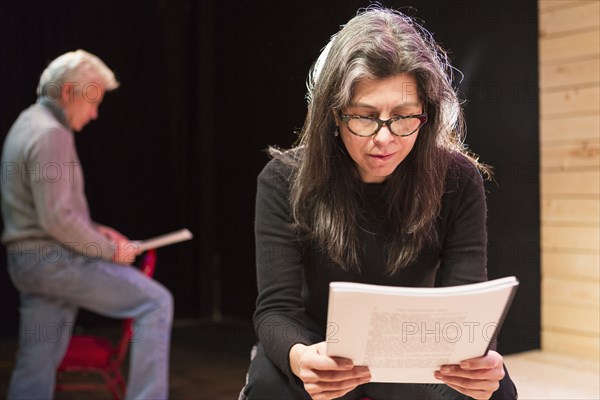 Hispanic man and woman reading scripts on theater stage