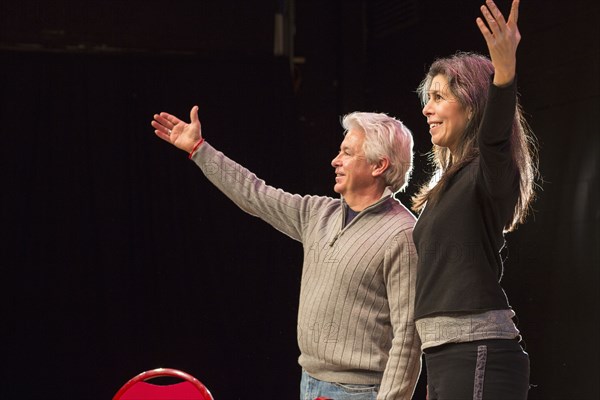 Hispanic man and woman with arms raised on theater stage