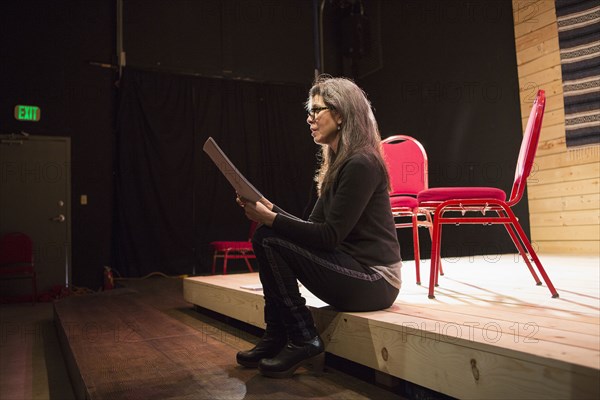 Hispanic woman reading script on theater stage