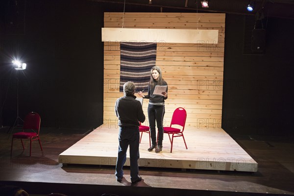 Hispanic man and woman reading scripts on theater stage