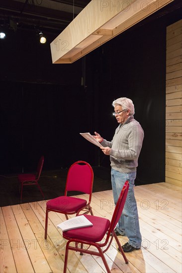 Hispanic man reading script on theater stage